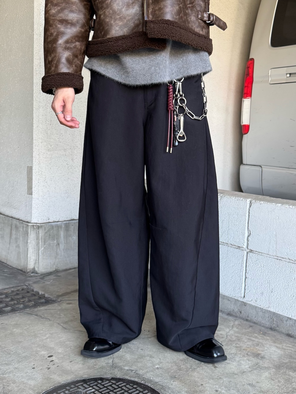 ブラック系のスラックス、グレー系のニット/セーター、ブラウン系のブルゾンを着用したメンズの秋コーディネートの8枚目の写真