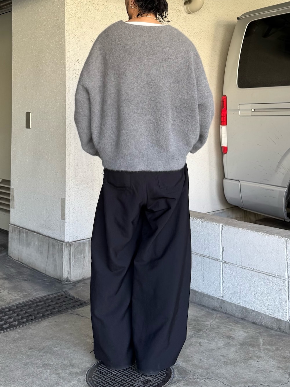 グレー系のニット/セーター、ブラック系のスラックスを着用したメンズの秋コーディネートの4枚目の写真