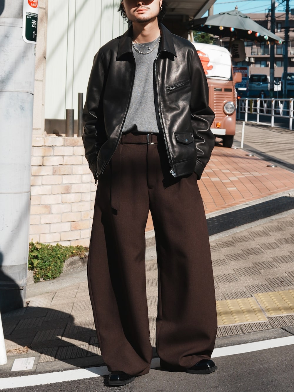 グレー系のスラックス、グレー系のニット/セーター、ブラック系のライダースジャケットを着用したメンズの冬コーディネートの3枚目の写真