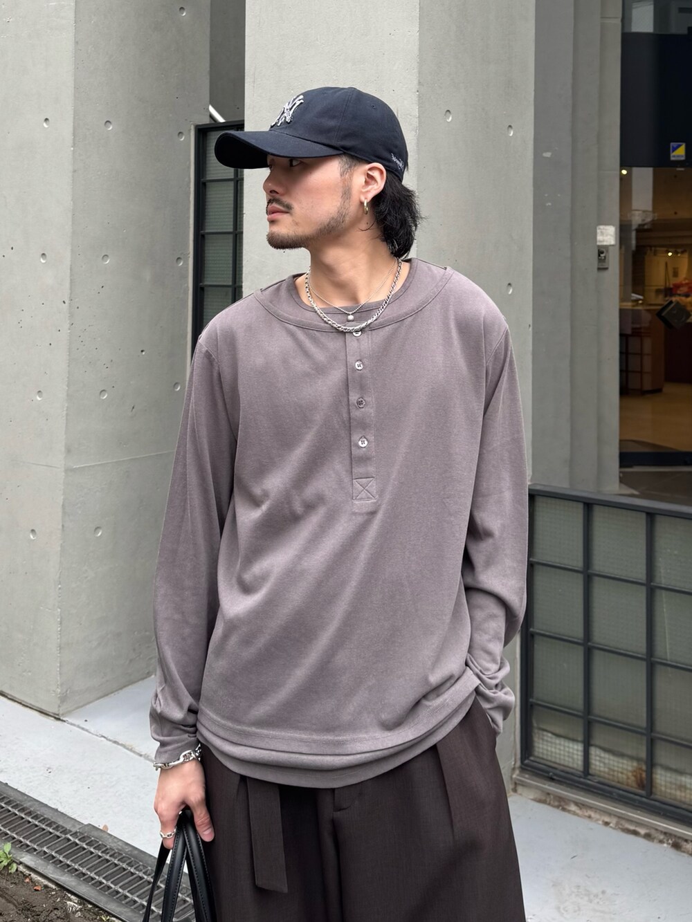 グレー系のスラックス、グレー系のTシャツ/カットソー、ブラック系のショルダーバッグを着用したメンズの春コーディネートの5枚目の写真