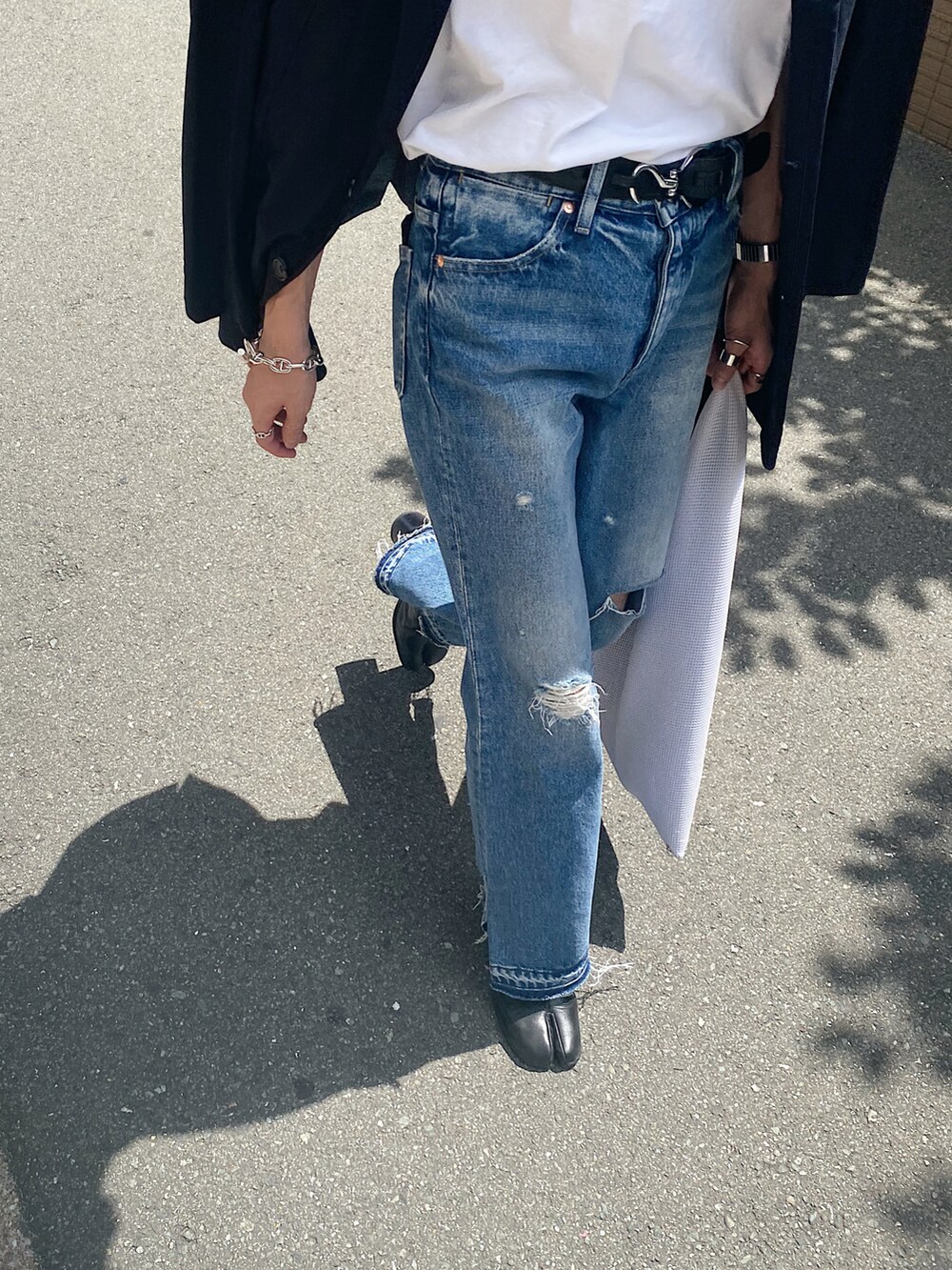 ホワイト系のTシャツ/カットソー、ブルー系のデニムパンツ、ホワイト系のバッグを着用したメンズの秋コーディネートの3枚目の写真