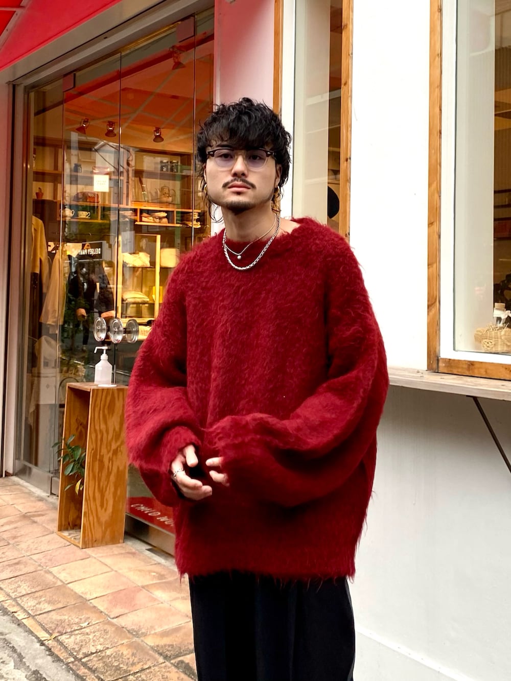 レッド系のニット/セーター、ブラック系のスラックス、ブラック系のローファーを着用したメンズの秋コーディネートの2枚目の写真