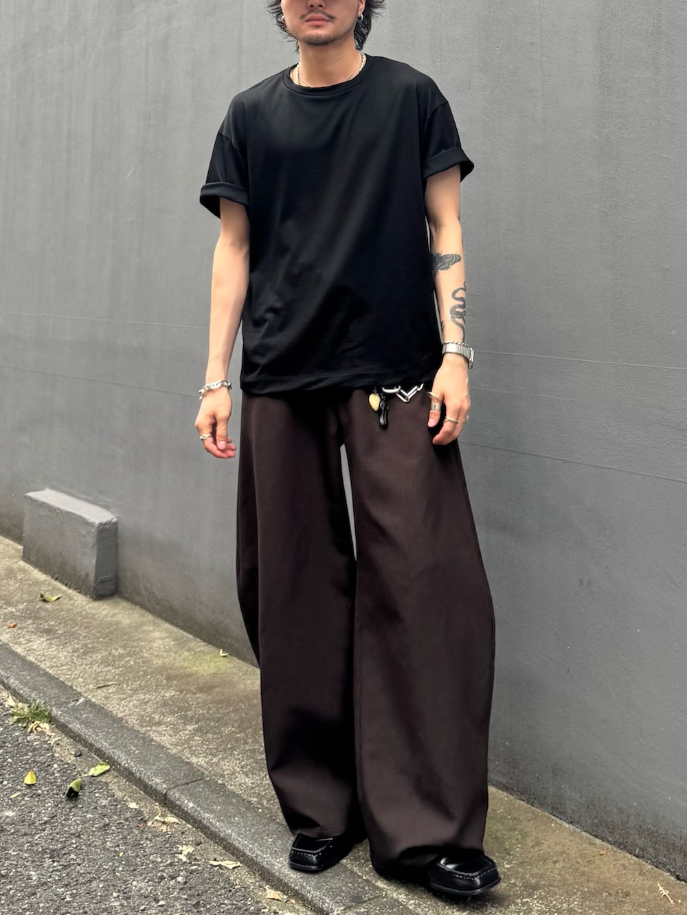 ブラック系のTシャツ/カットソー、グレー系のスラックスを着用したメンズの夏コーディネートの4枚目の写真