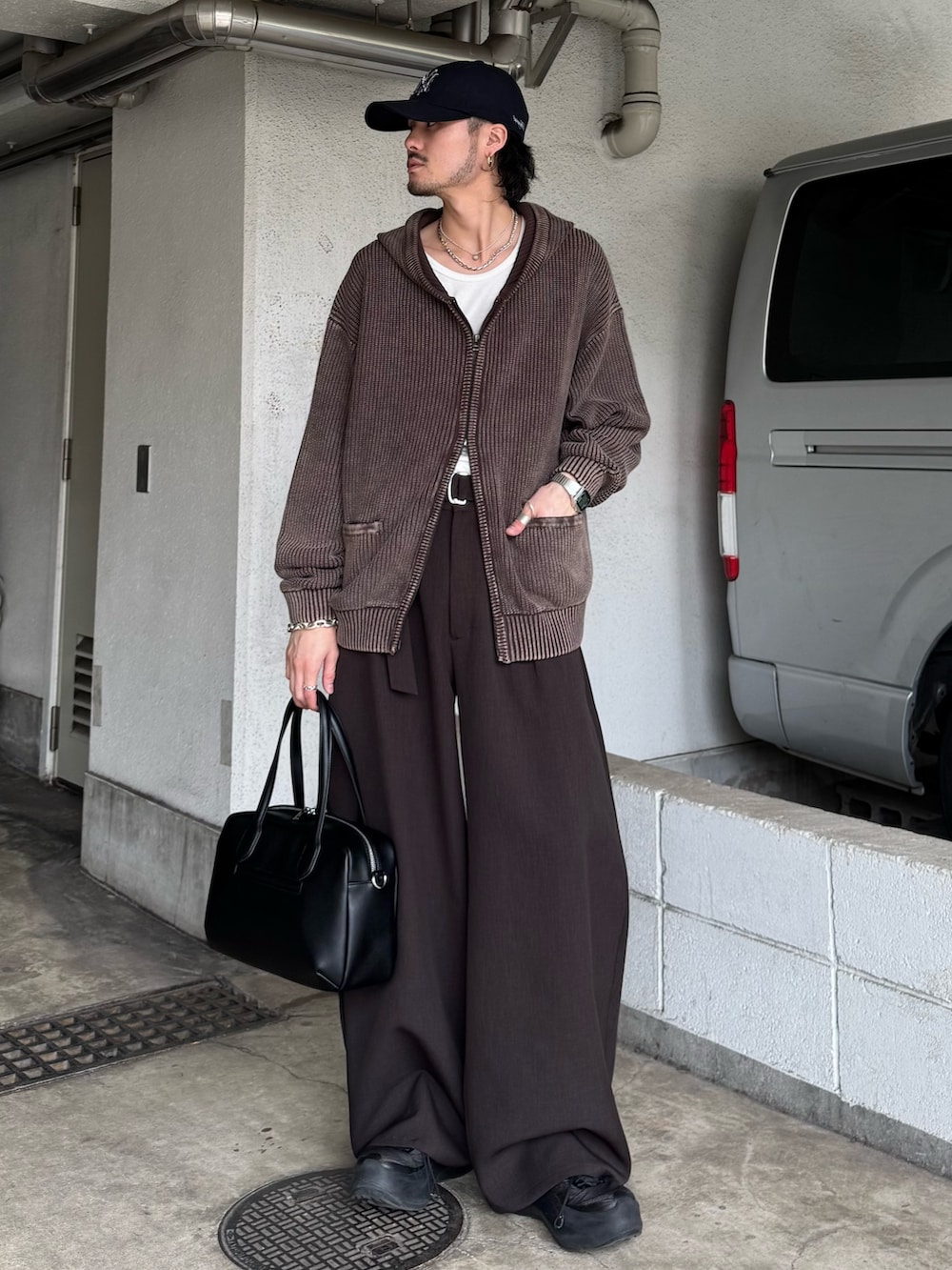 ブラウン系のパーカー、グレー系のスラックス、ブラック系のショルダーバッグを着用したメンズの春コーディネートの4枚目の写真