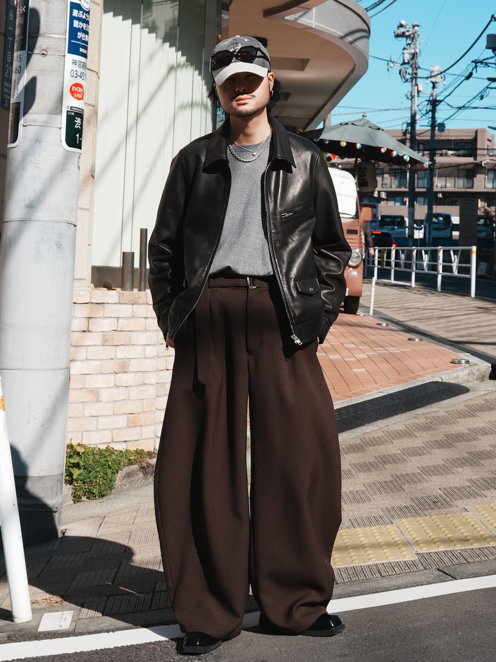 グレー系のスラックス、グレー系のニット/セーター、ブラック系のライダースジャケットを着用したメンズの冬コーディネートの2枚目の写真