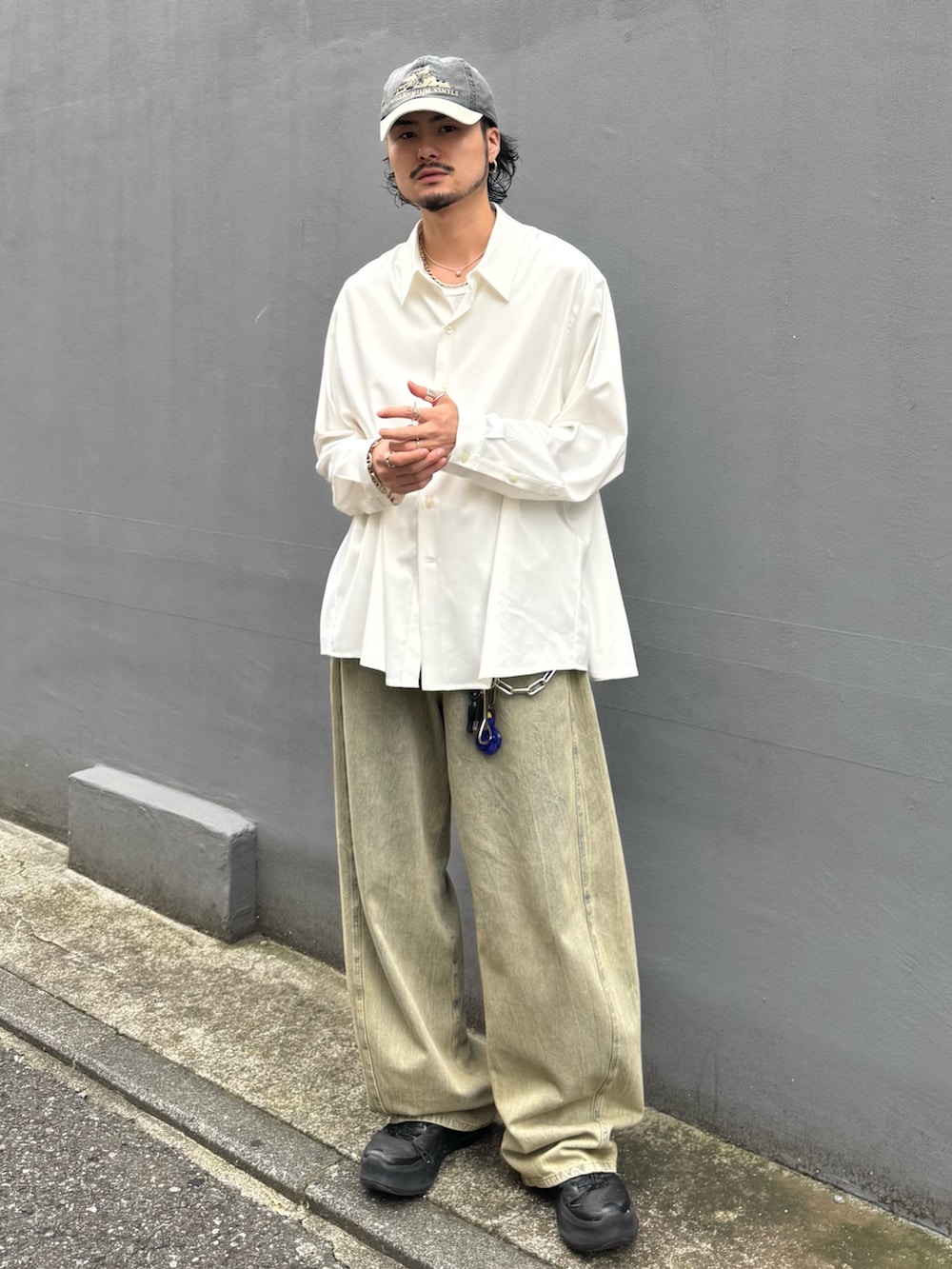 ホワイト系のトップス、グリーン系のデニムパンツを着用したメンズの夏コーディネートの2枚目の写真