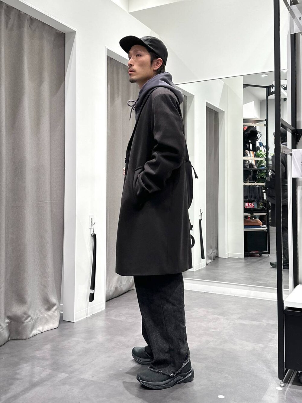 ブラック系のスニーカー、ブラック系のチェスターコート、ブラック系のデニムパンツを着用したメンズの冬コーディネートの3枚目の写真