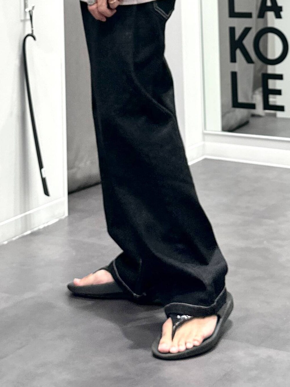 ブラック系のデニムパンツ、ベージュ系のTシャツ/カットソー、グレー系のショルダーバッグを着用したメンズの夏コーディネートの3枚目の写真