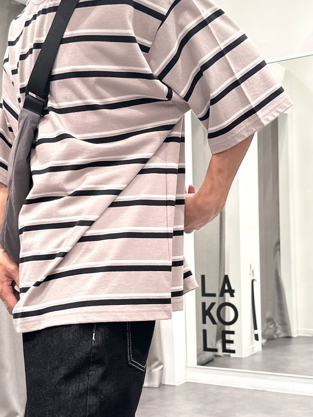 ブラック系のデニムパンツ、ベージュ系のTシャツ/カットソー、グレー系のショルダーバッグを着用したメンズの夏コーディネートの7枚目の写真