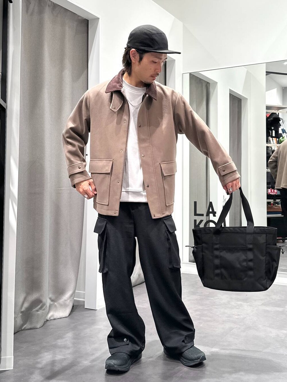 ブラック系のスニーカー、ベージュ系のブルゾン、ブラック系のトートバッグを着用したメンズの冬コーディネートの2枚目の写真