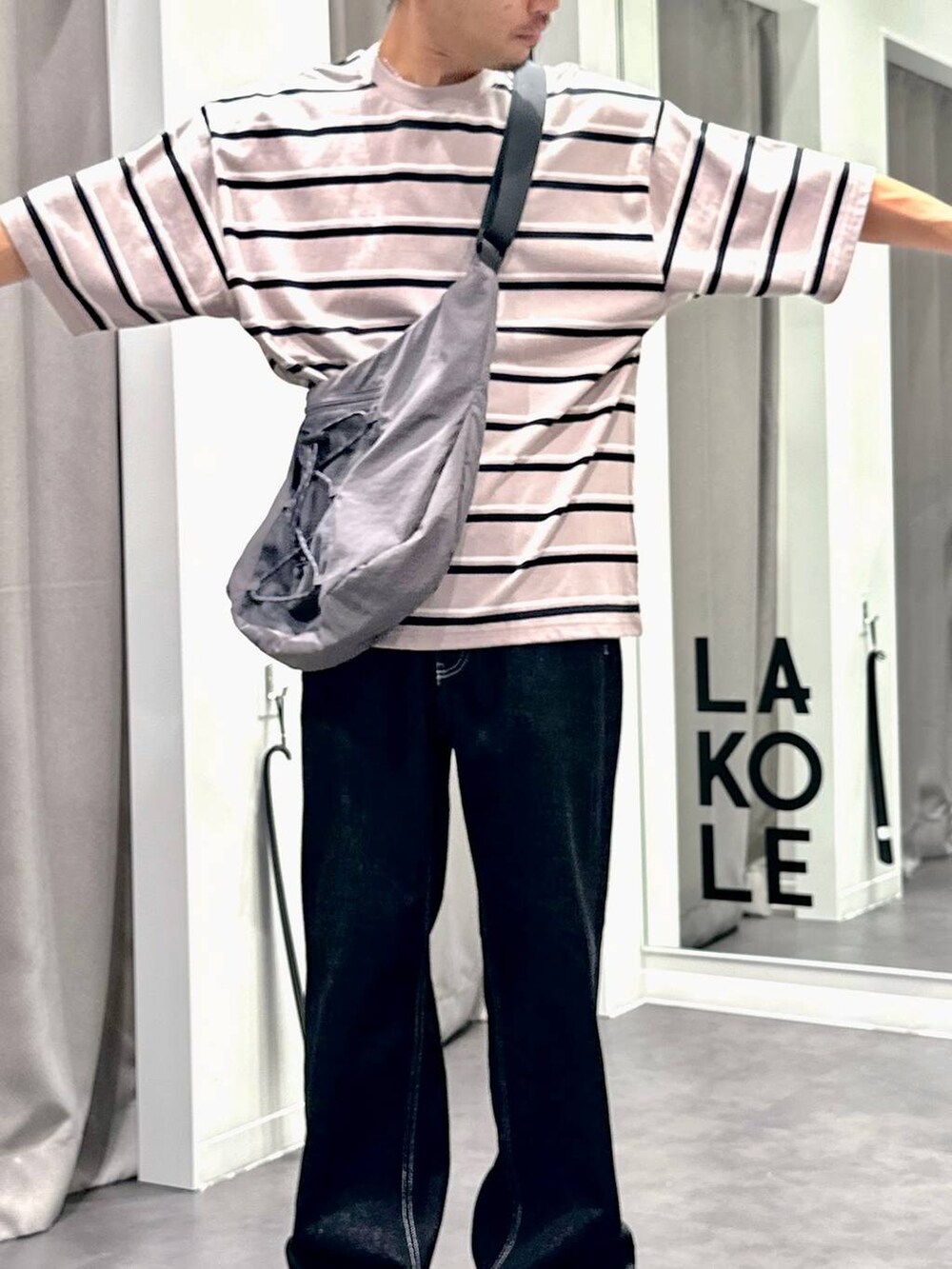 ブラック系のデニムパンツ、ベージュ系のTシャツ/カットソー、グレー系のショルダーバッグを着用したメンズの夏コーディネートの6枚目の写真