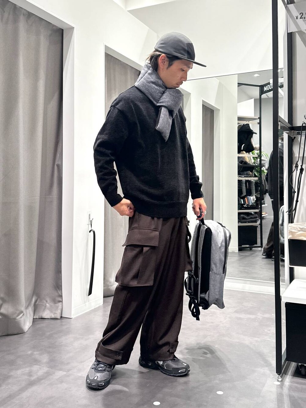 ブラック系のニット/セーター、グレー系のバックパック/リュック、ブラウン系のカーゴパンツを着用したメンズの秋コーディネートの2枚目の写真