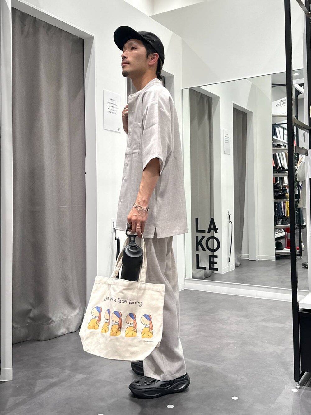 ブラック系のサンダル、ホワイト系のシャツ/ブラウス、その他のエコバッグ/サブバッグを着用したメンズの春コーディネートの2枚目の写真