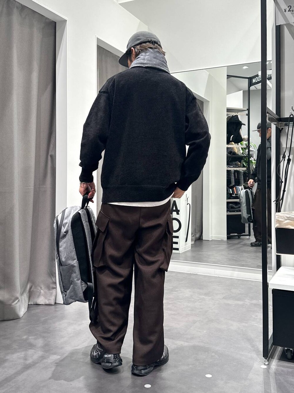 ブラック系のニット/セーター、グレー系のバックパック/リュック、ブラウン系のカーゴパンツを着用したメンズの秋コーディネートの4枚目の写真