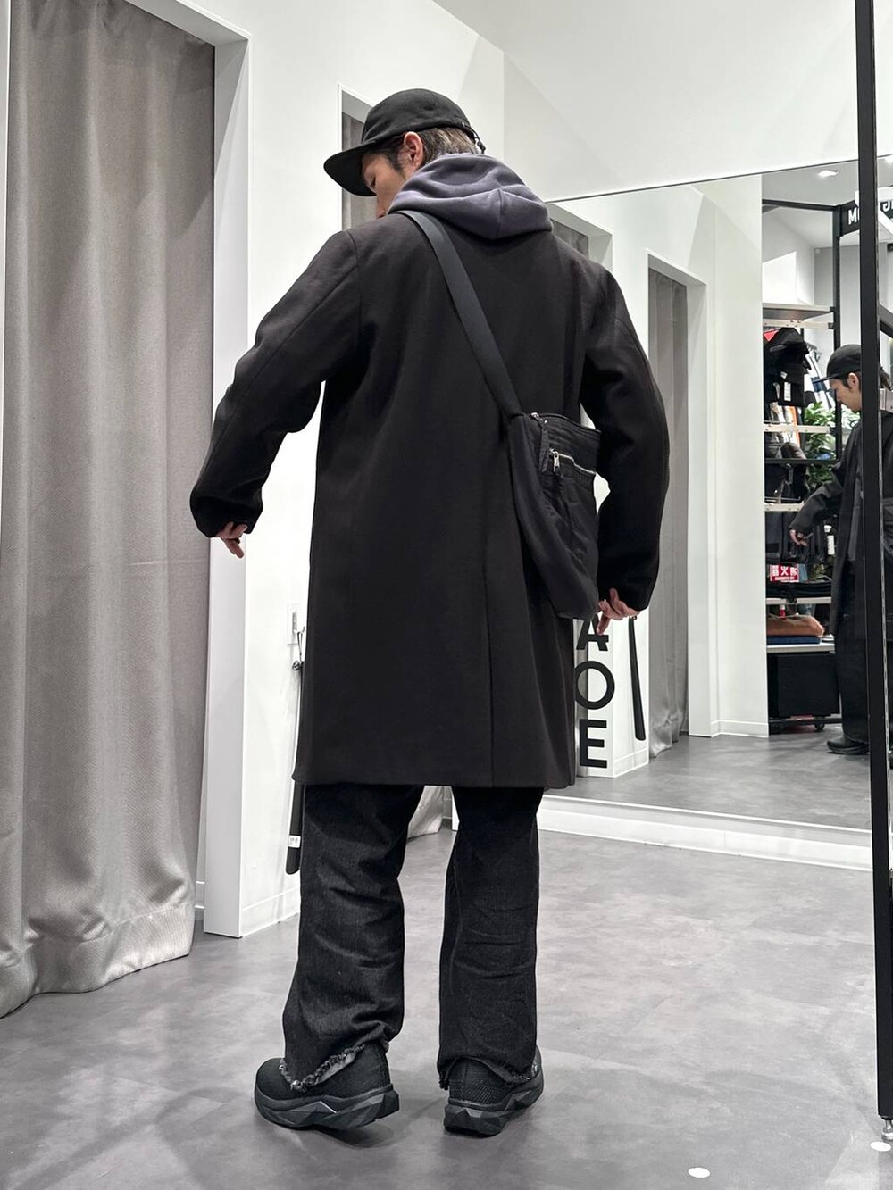 ブラック系のスニーカー、ブラック系のチェスターコート、ブラック系のデニムパンツを着用したメンズの冬コーディネートの4枚目の写真