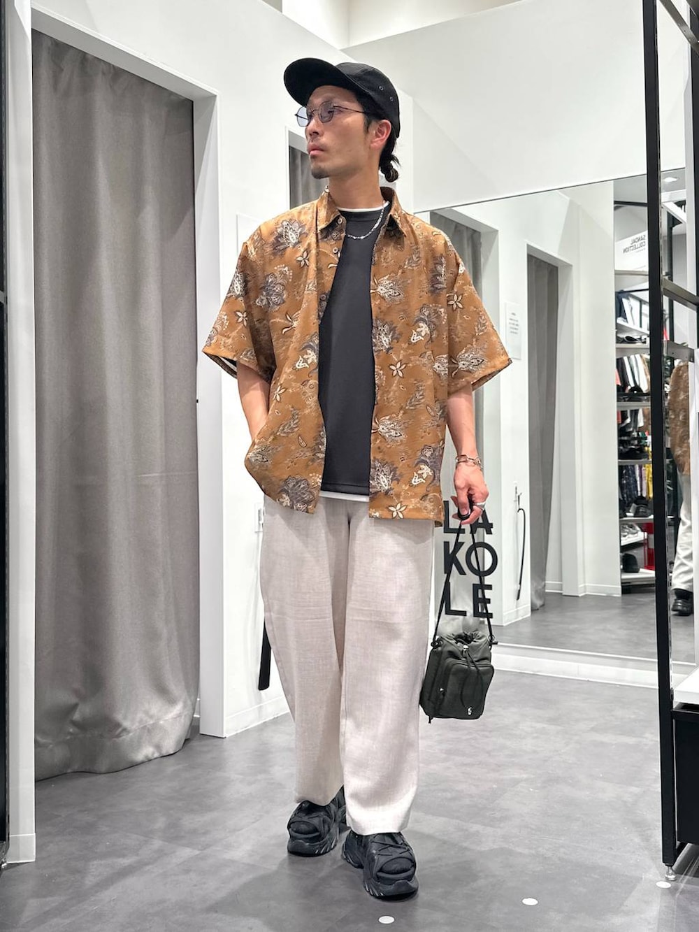 ブラック系のサンダル、ホワイト系のその他パンツ、グリーン系のショルダーバッグを着用したメンズの春コーディネートの2枚目の写真