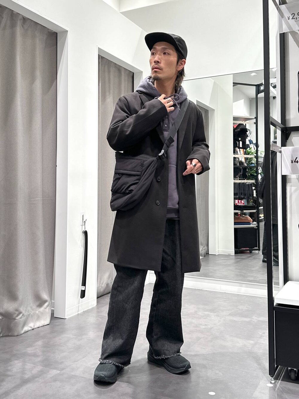 ブラック系のスニーカー、ブラック系のチェスターコート、ブラック系のデニムパンツを着用したメンズの冬コーディネートの2枚目の写真