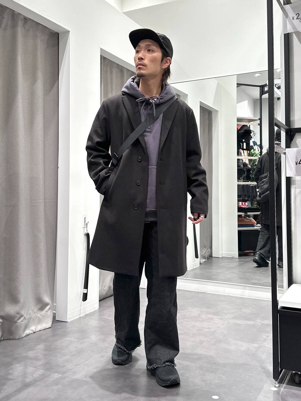 ブラック系のスニーカー、ブラック系のチェスターコート、ブラック系のデニムパンツを着用したメンズの冬コーディネートの5枚目の写真