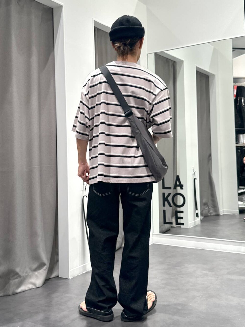 ブラック系のデニムパンツ、ベージュ系のTシャツ/カットソー、グレー系のショルダーバッグを着用したメンズの夏コーディネートの2枚目の写真