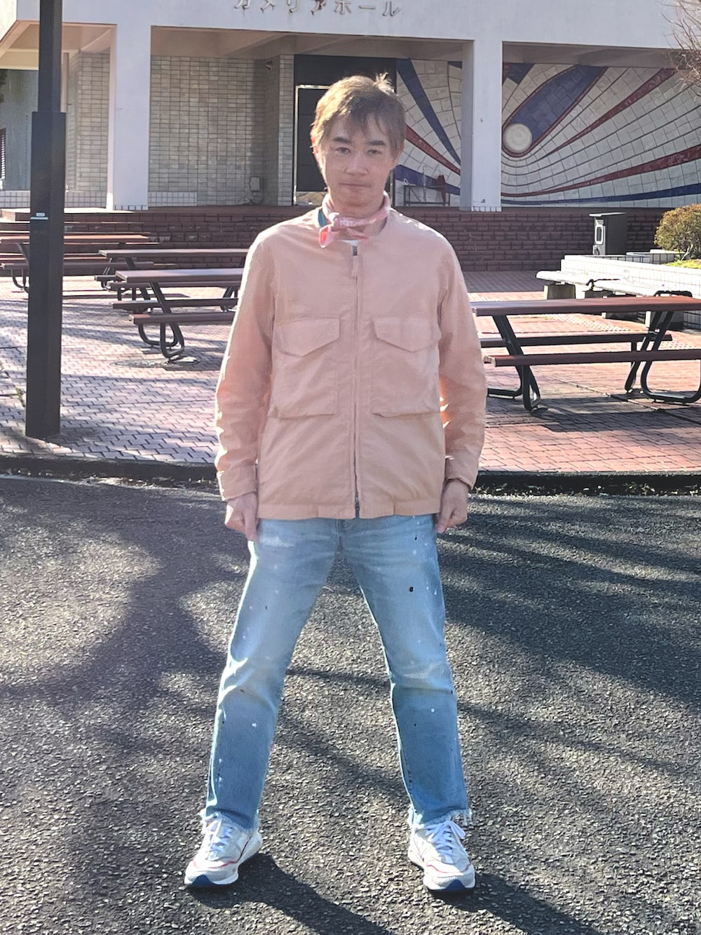 ホワイト系のスニーカー、ピンク系のノーカラージャケット、ブルー系のデニムパンツを着用したメンズの春コーディネートの2枚目の写真