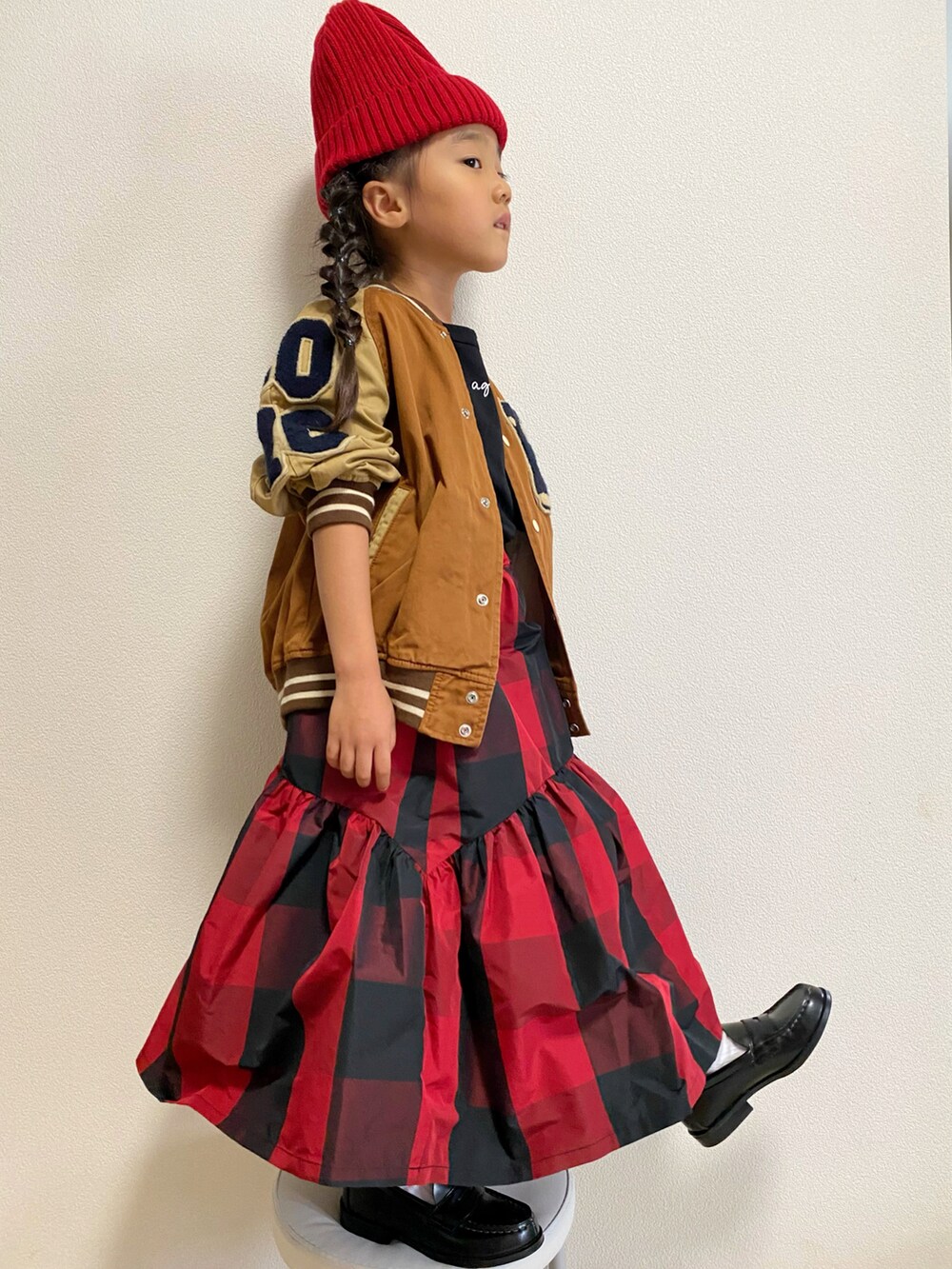 ブラウン系のスタジャン、ブラック系のTシャツ/カットソー、レッド系のスカートを着用したキッズの秋コーディネートの2枚目の写真