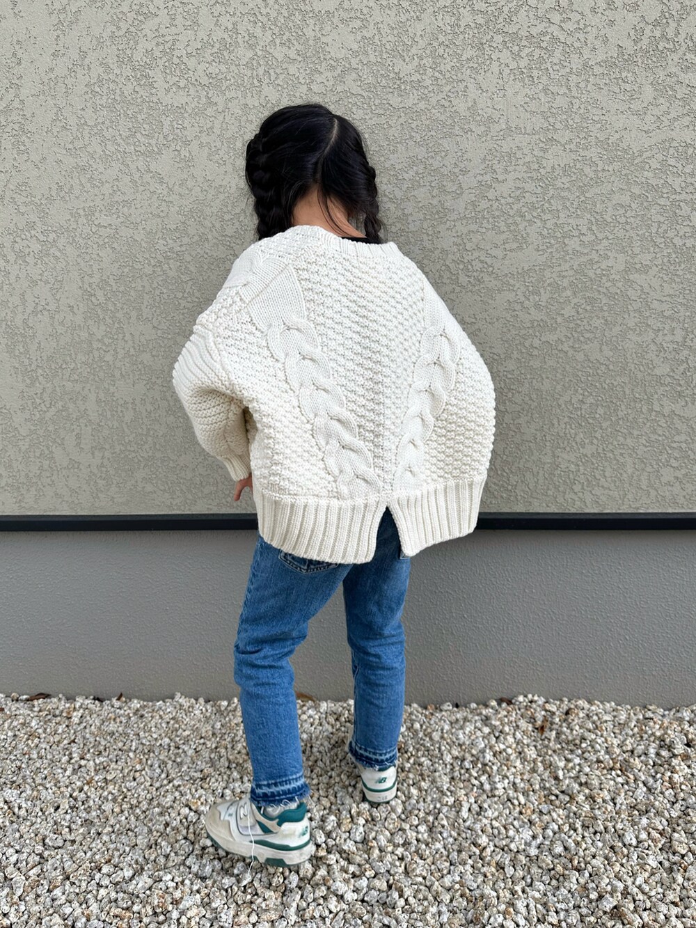 ホワイト系のカーディガン/ボレロ、ブラック系のTシャツ/カットソー、ブルー系のデニムパンツを着用したキッズの冬コーディネートの2枚目の写真