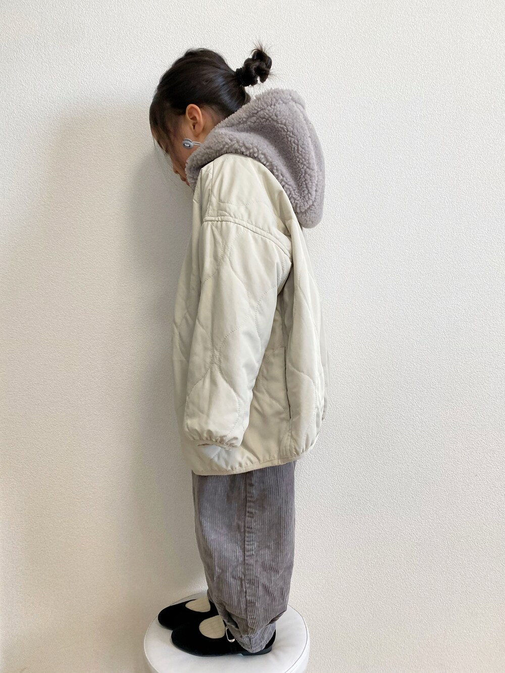 ホワイト系のマウンテンパーカー、ブルー系のニット/セーター、グレー系のパンツを着用したキッズの冬コーディネートの3枚目の写真