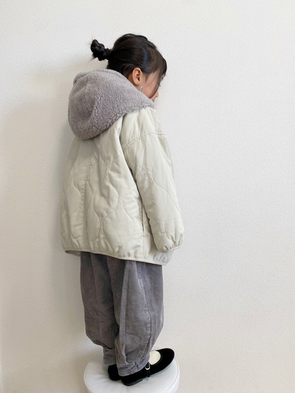 ホワイト系のマウンテンパーカー、ブルー系のニット/セーター、グレー系のパンツを着用したキッズの冬コーディネートの2枚目の写真