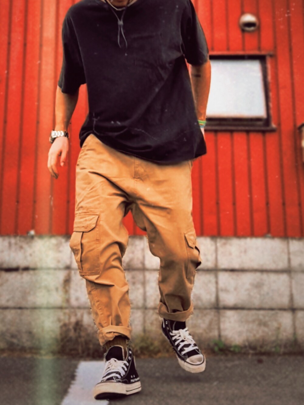 ブラック系のTシャツ/カットソー、ベージュ系のチノパンツ、ブラック系のスニーカーを着用したメンズの夏コーディネートの2枚目の写真