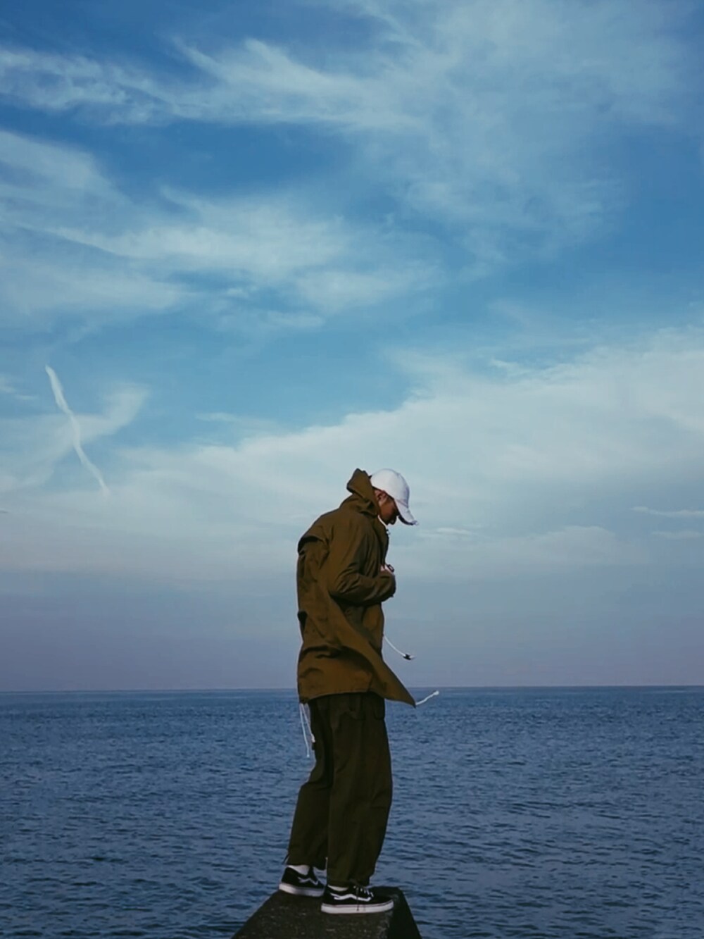 グリーン系のミリタリージャケット、ホワイト系のTシャツ/カットソー、ブラウン系のチノパンツを着用したメンズの春コーディネートの2枚目の写真