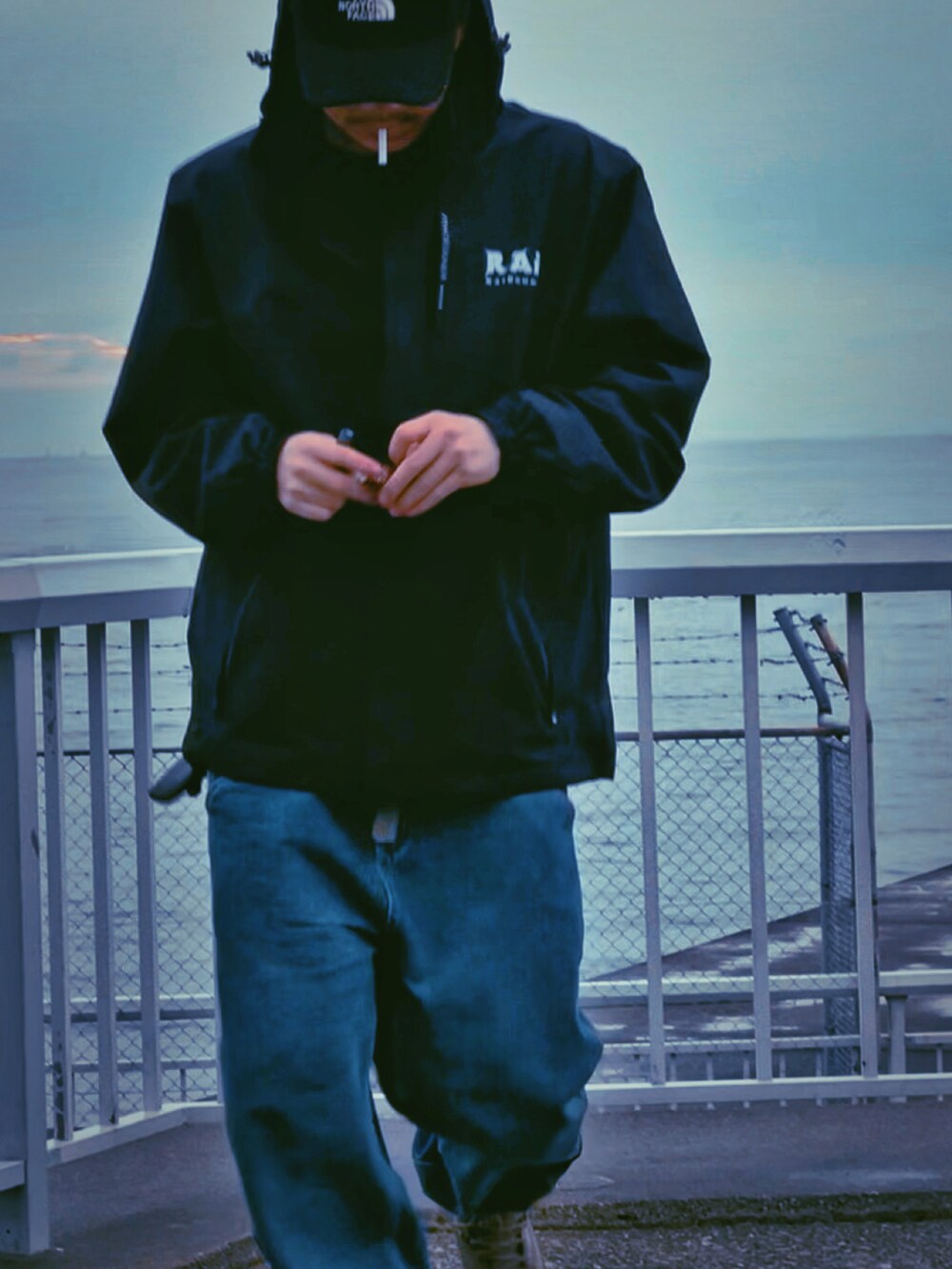 ブラック系のマウンテンパーカー、ブルー系のデニムパンツ、グレー系のブーツを着用したメンズの冬コーディネートの2枚目の写真