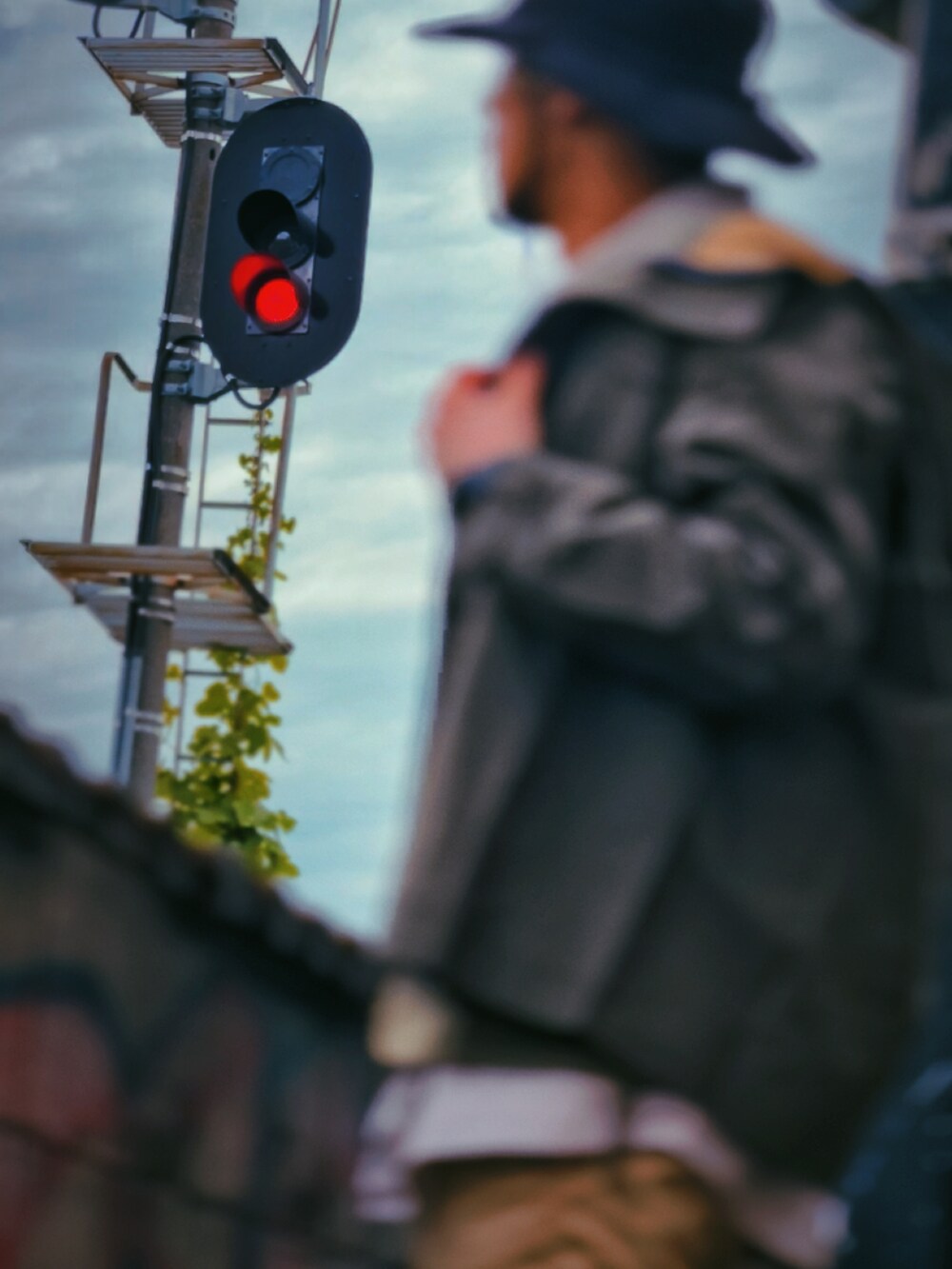 グリーン系のミリタリージャケット、ベージュ系のベスト、ベージュ系のカーゴパンツを着用したメンズの春コーディネートの2枚目の写真