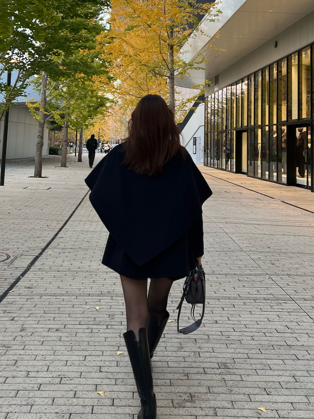 ブラック系のTシャツ/カットソー、ブラック系のブーツ、ブルー系のノーカラーコートを着用したレディースの秋コーディネートの4枚目の写真