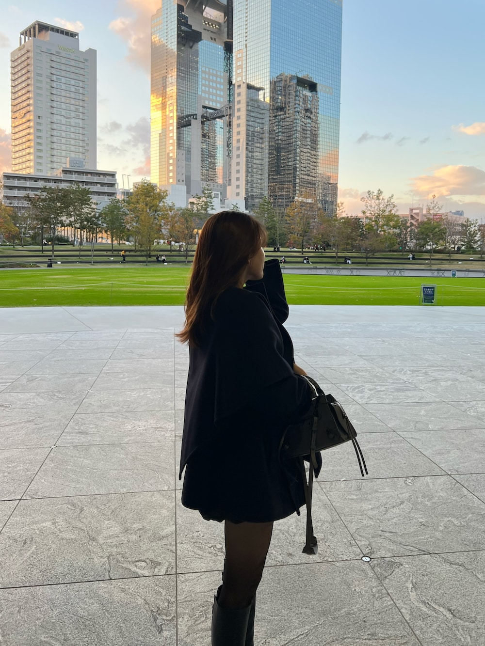 ブラック系のTシャツ/カットソー、ブラック系のブーツ、ブルー系のノーカラーコートを着用したレディースの秋コーディネートの3枚目の写真