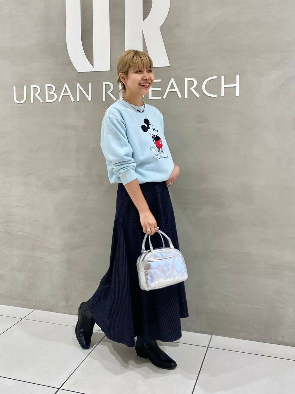 ブラック系のブーツ、シルバー系のショルダーバッグ、ブルー系のスカートを着用したレディースの秋コーディネートの3枚目の写真