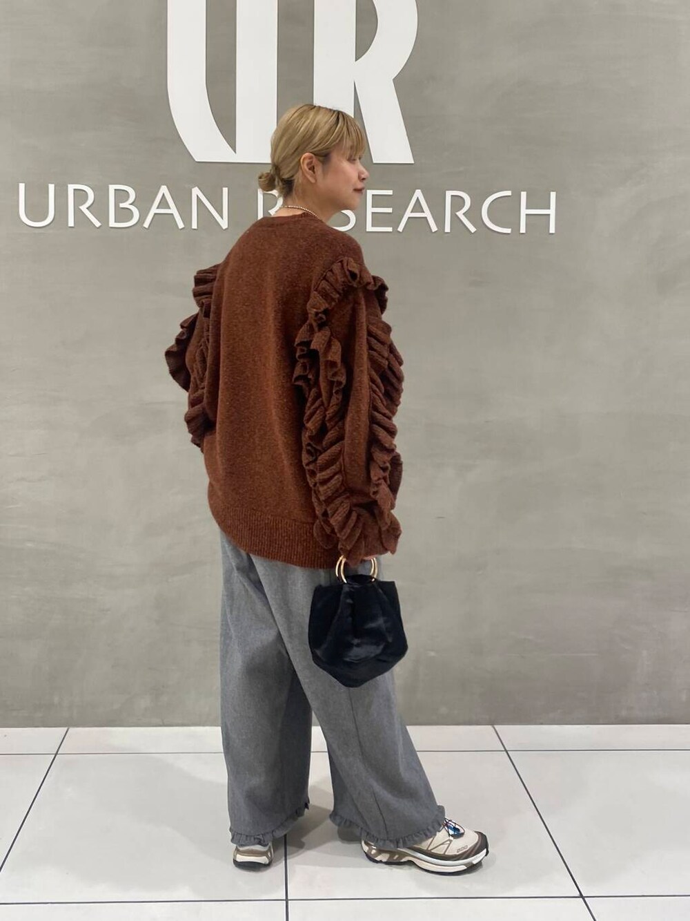 ブラック系のハンドバッグ、グレー系のその他パンツ、ブラウン系のニット/セーターを着用したレディースの秋コーディネートの2枚目の写真