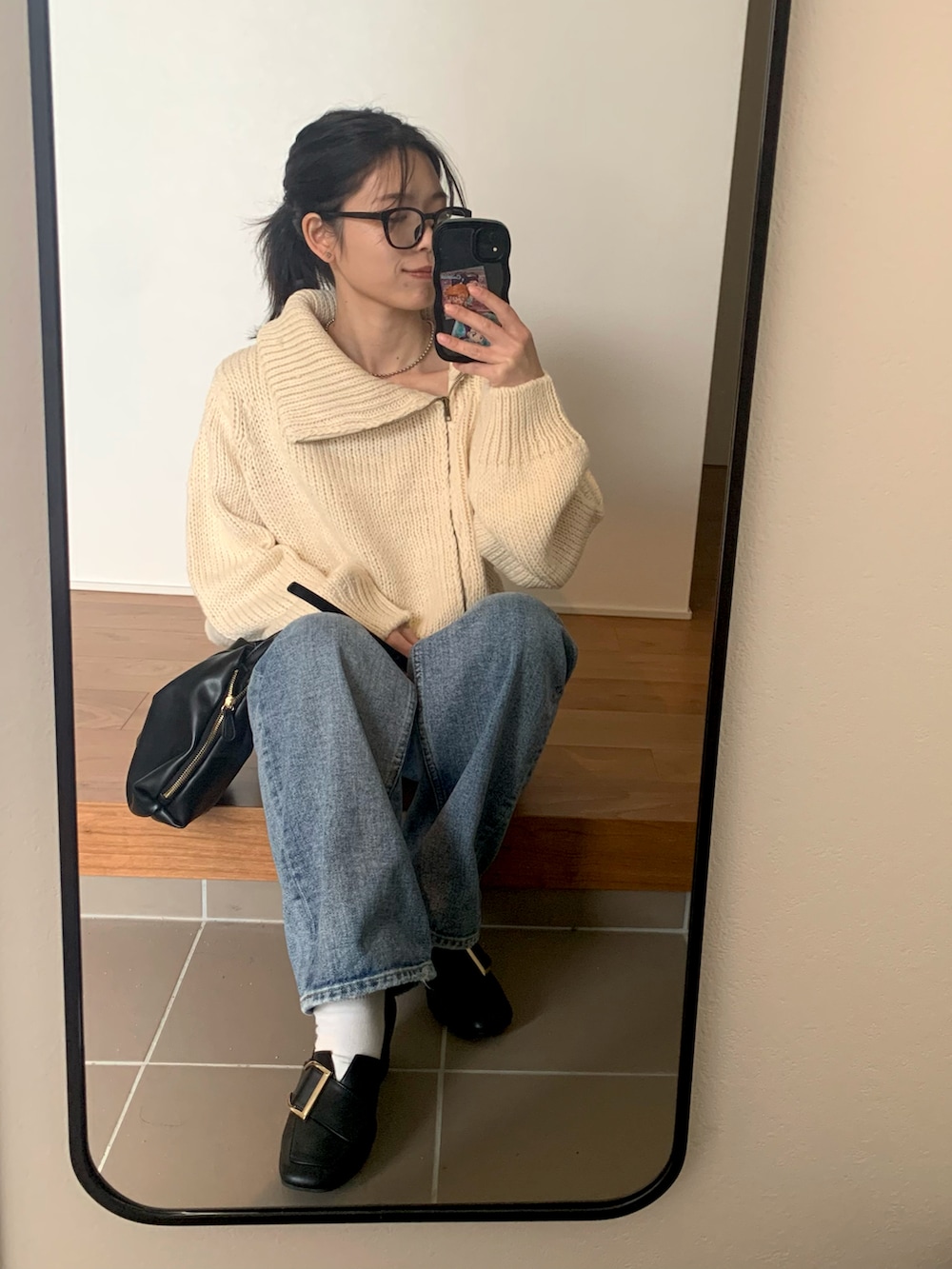 ホワイト系のニット/セーター、ブラック系のショルダーバッグ、ブルー系のデニムパンツを着用したレディースの冬コーディネートの3枚目の写真