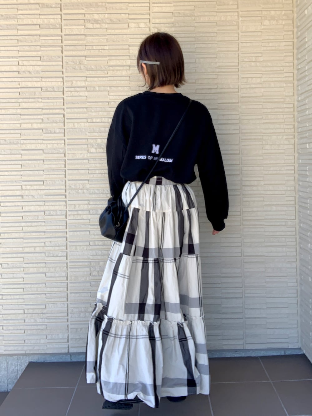 ブラック系のスウェット、ホワイト系のスカート、ブラック系のブーツを着用したレディースの冬コーディネートの2枚目の写真