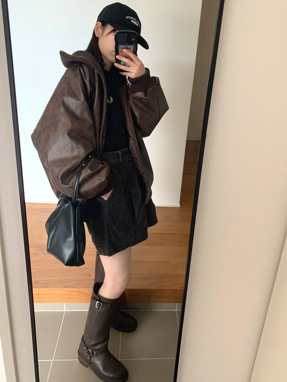 ブラック系のニット/セーター、ブラウン系のブーツ、ブラウン系のブルゾンを着用したレディースの冬コーディネートの2枚目の写真