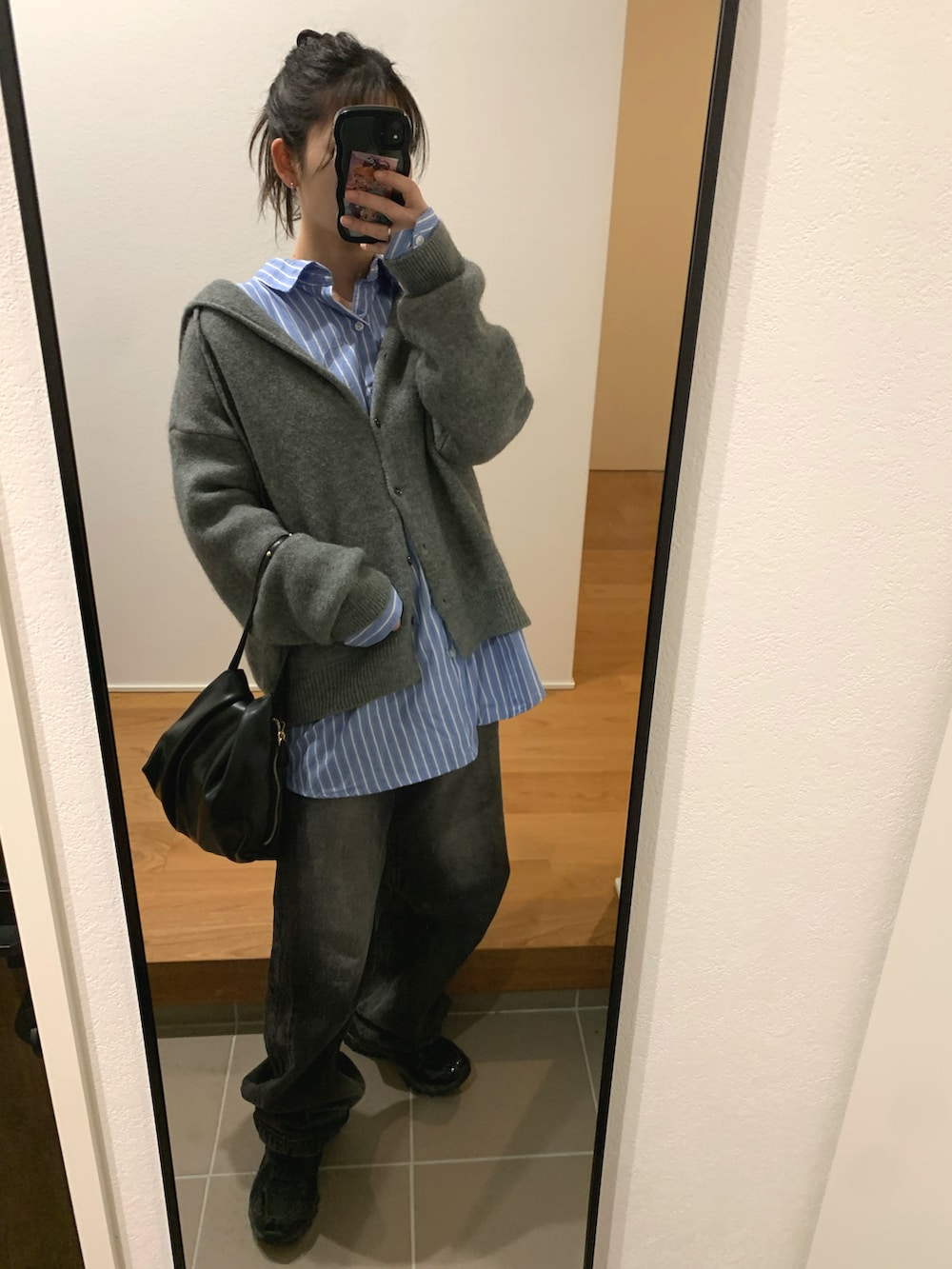 グレー系のニット/セーター、ブルー系のシャツ/ブラウス、ブラック系のデニムパンツを着用したレディースの冬コーディネートの2枚目の写真