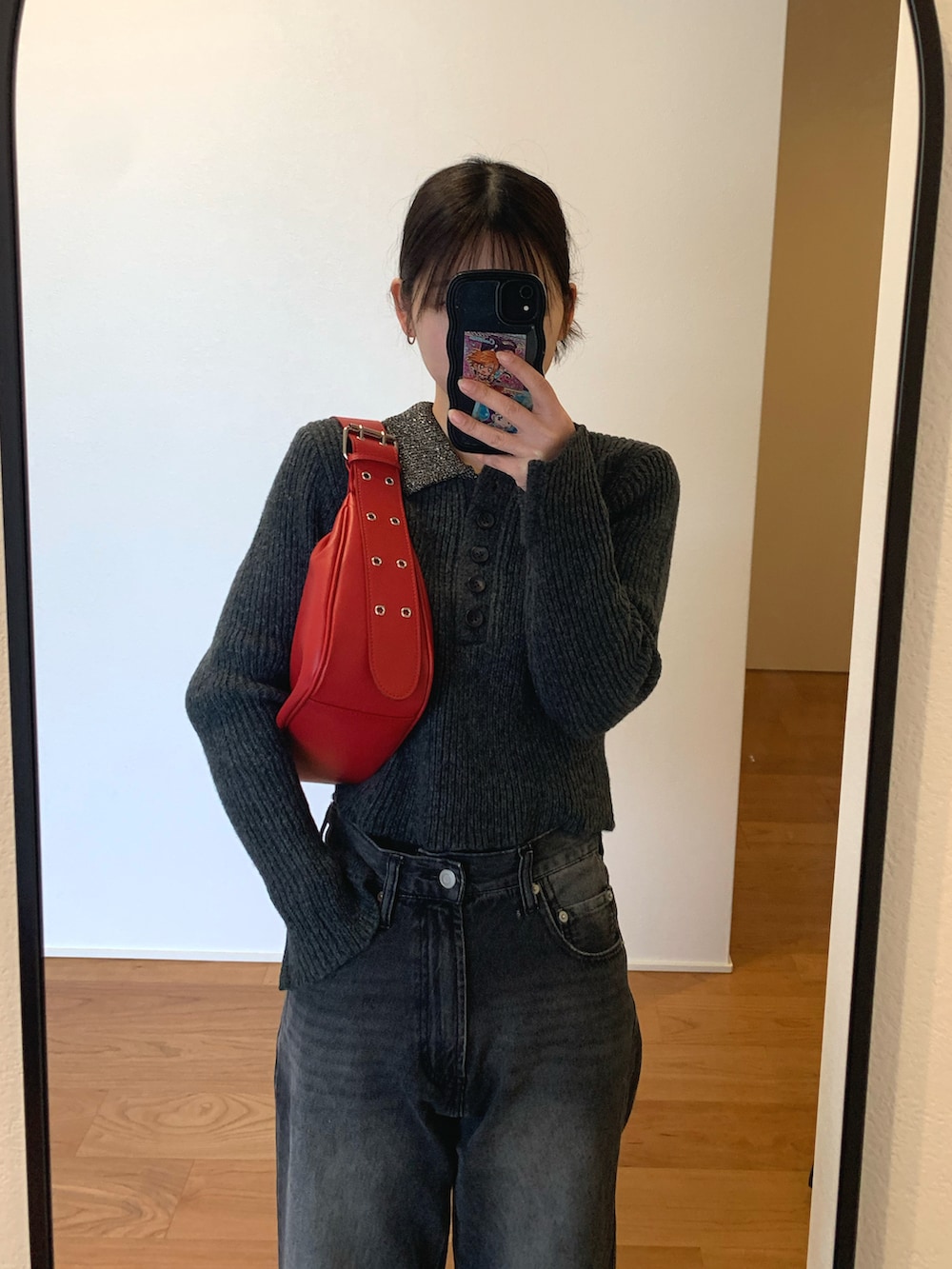 グレー系のニット/セーター、レッド系のハンドバッグ、ブラック系のデニムパンツを着用したレディースの冬コーディネートの2枚目の写真