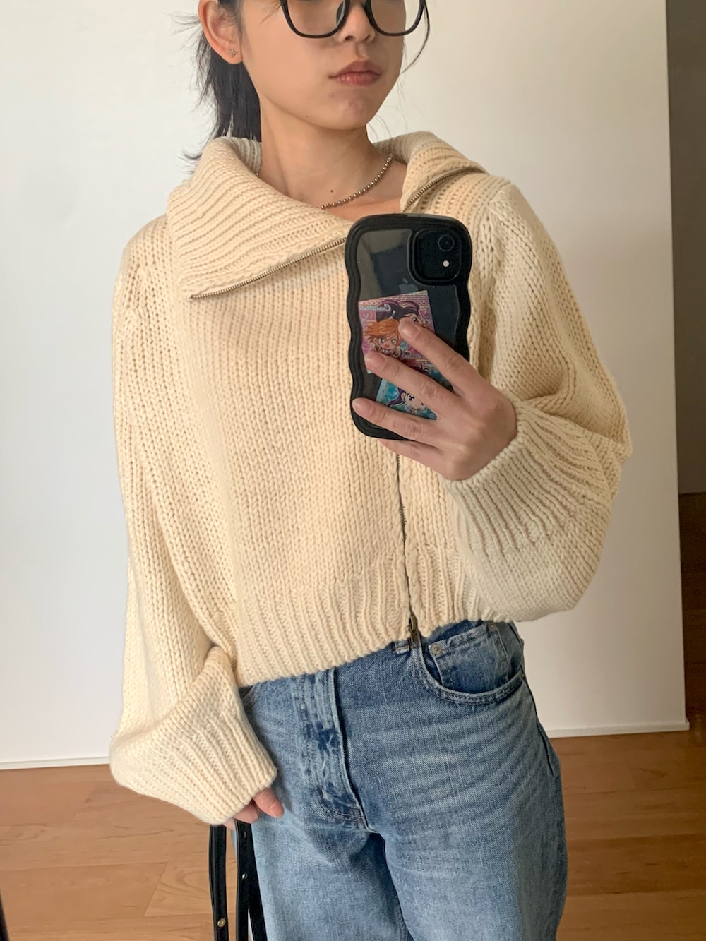 ホワイト系のニット/セーター、ブラック系のショルダーバッグ、ブルー系のデニムパンツを着用したレディースの冬コーディネートの4枚目の写真