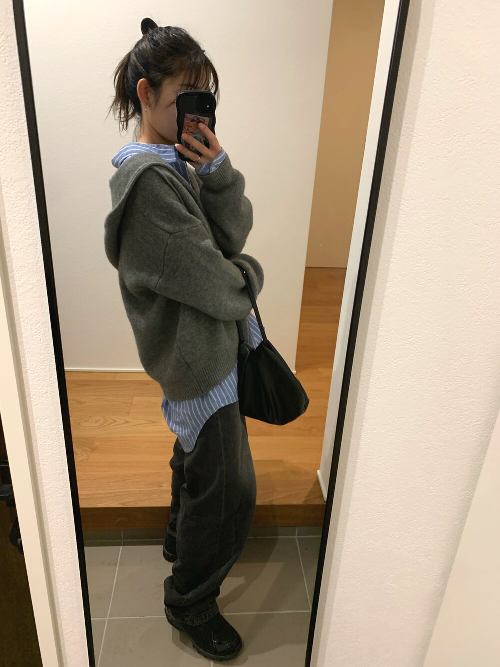 グレー系のニット/セーター、ブルー系のシャツ/ブラウス、ブラック系のデニムパンツを着用したレディースの冬コーディネートの3枚目の写真