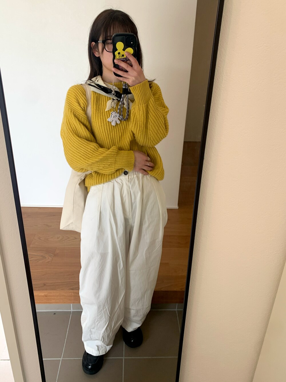 イエロー系のニット/セーター、ホワイト系のチノパンツ、ブラック系のローファーを着用したレディースの春コーディネートの2枚目の写真