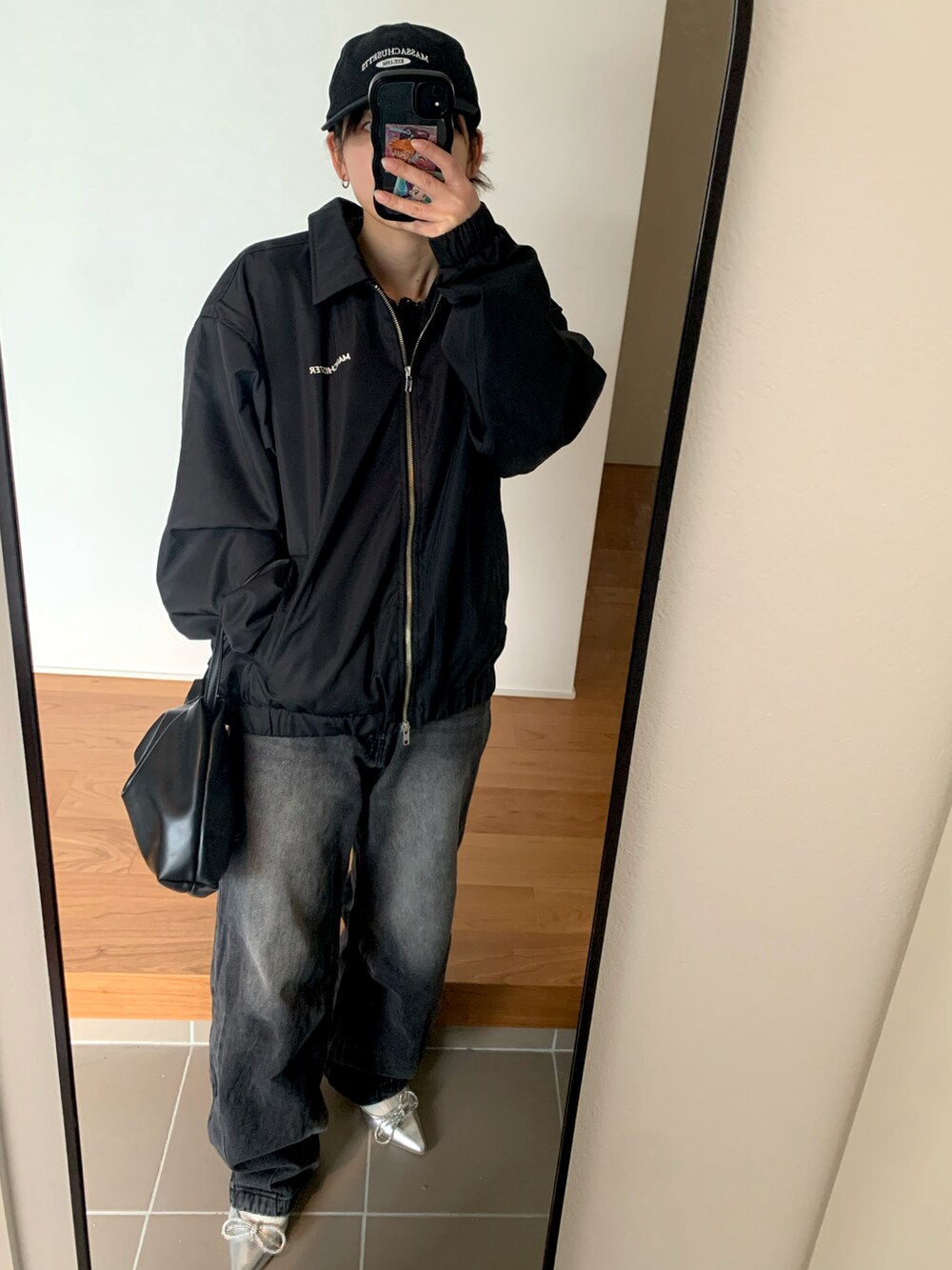 シルバー系のパンプス、ブラック系のデニムパンツ、ブラック系のブルゾンを着用したレディースの冬コーディネートの2枚目の写真