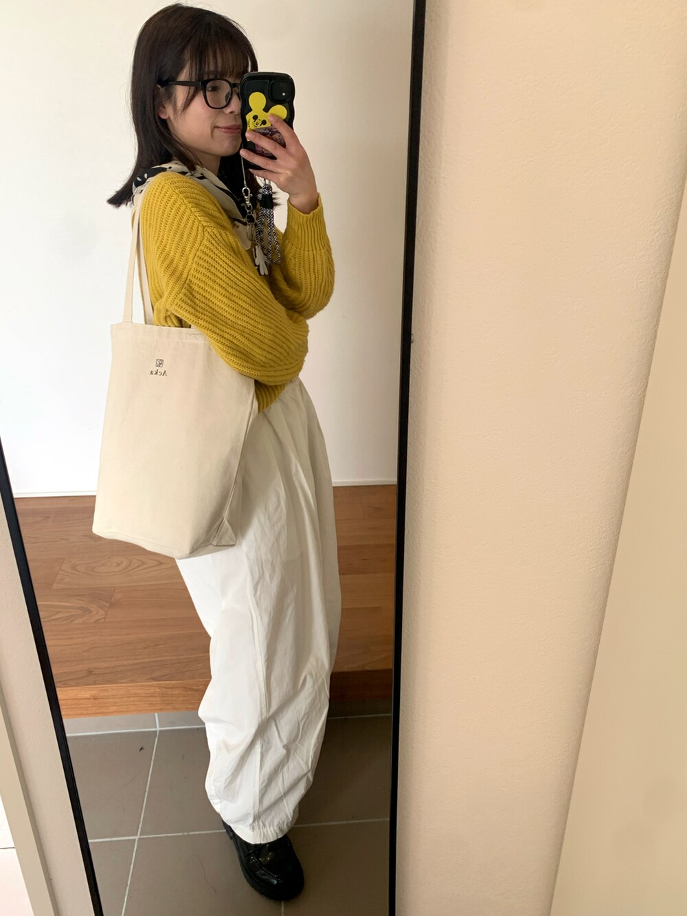 イエロー系のニット/セーター、ホワイト系のチノパンツ、ブラック系のローファーを着用したレディースの春コーディネートの3枚目の写真