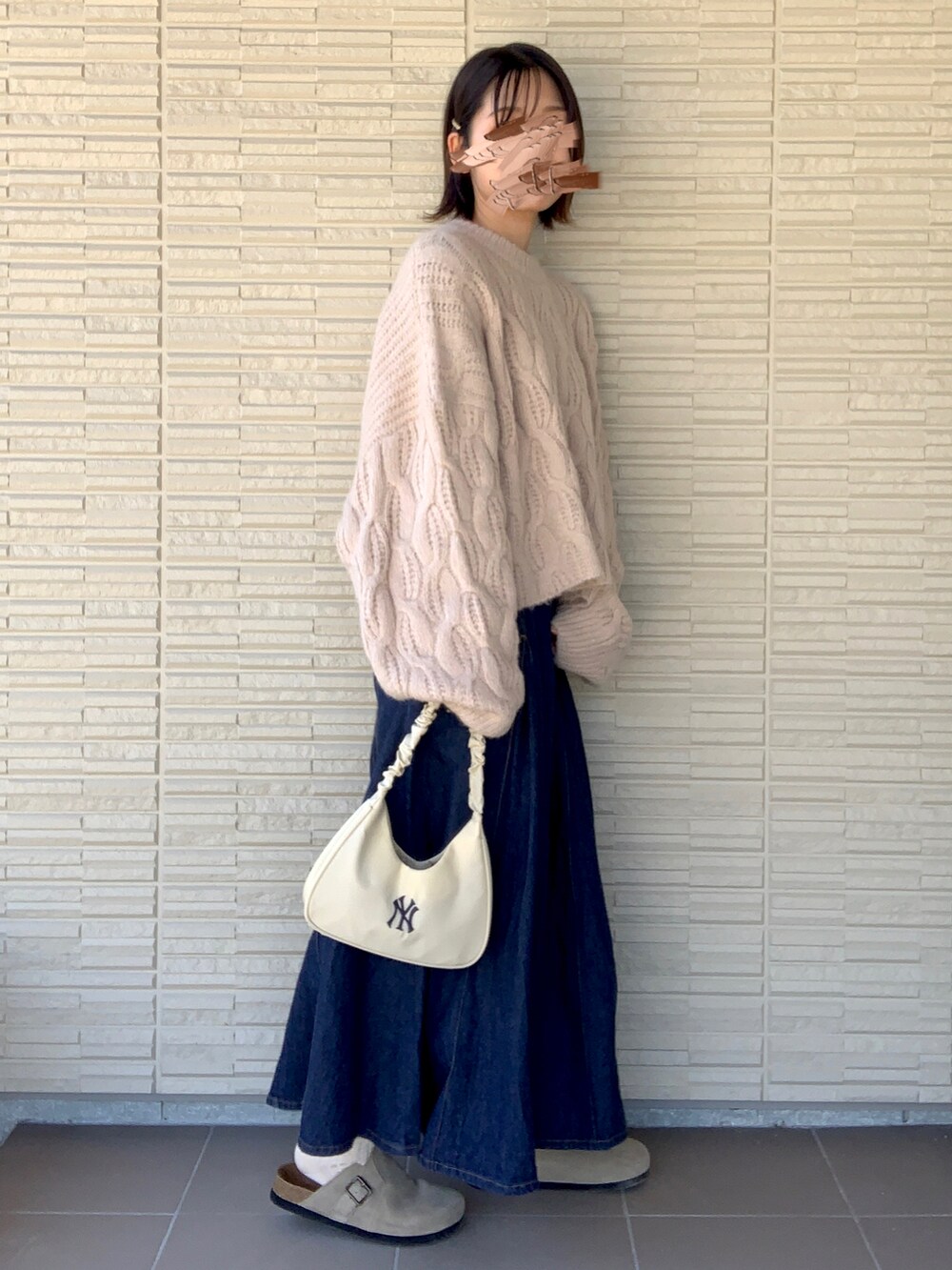 ホワイト系のニット/セーター、ベージュ系のハンドバッグを着用したレディースの秋コーディネートの2枚目の写真