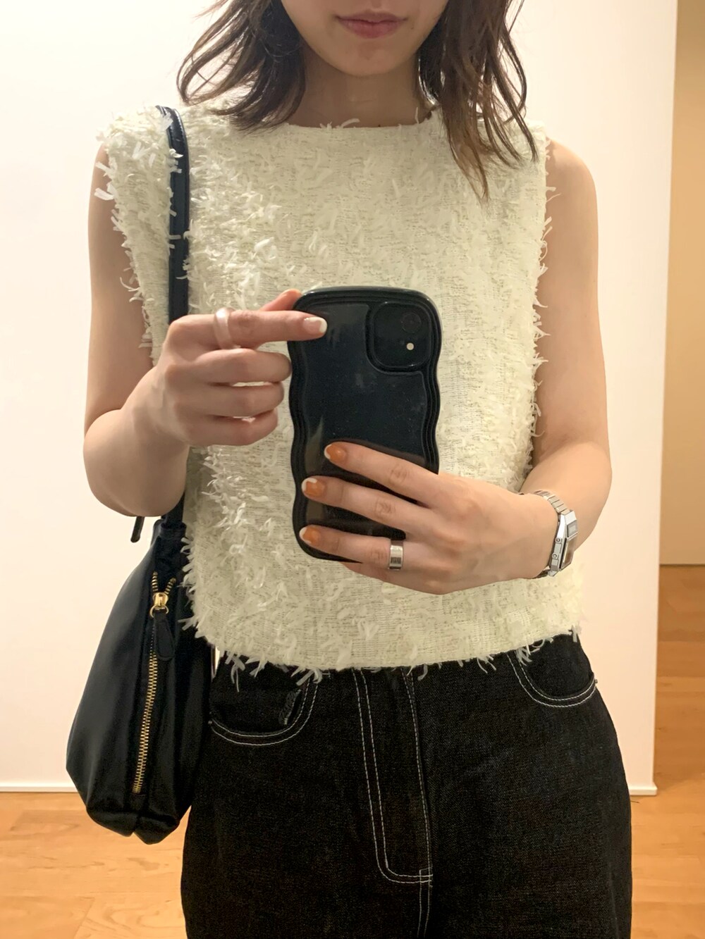 ホワイト系のベスト、ベージュ系のキャミソール、ブラック系のデニムパンツを着用したレディースの夏コーディネートの2枚目の写真