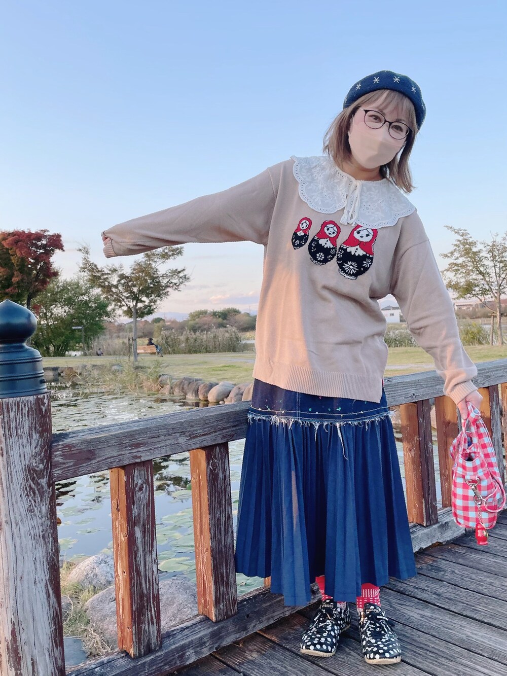 ベージュ系のニット/セーター、ブルー系のショルダーバッグ、ブルー系のスカートを着用したレディースの秋コーディネートの2枚目の写真