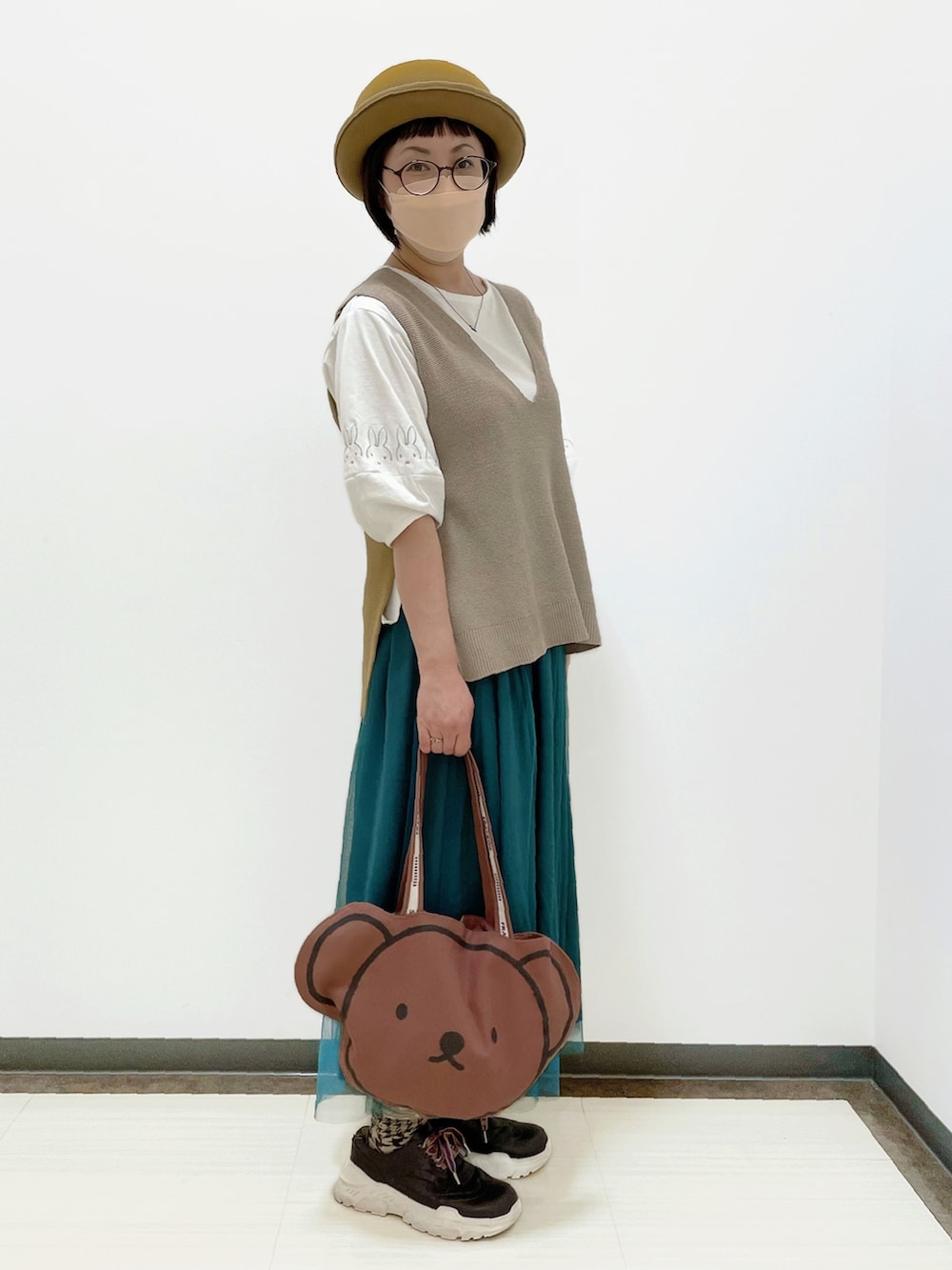 ホワイト系のトップス、ベージュ系のベスト、ブルー系のスカートを着用したレディースの秋コーディネートの3枚目の写真